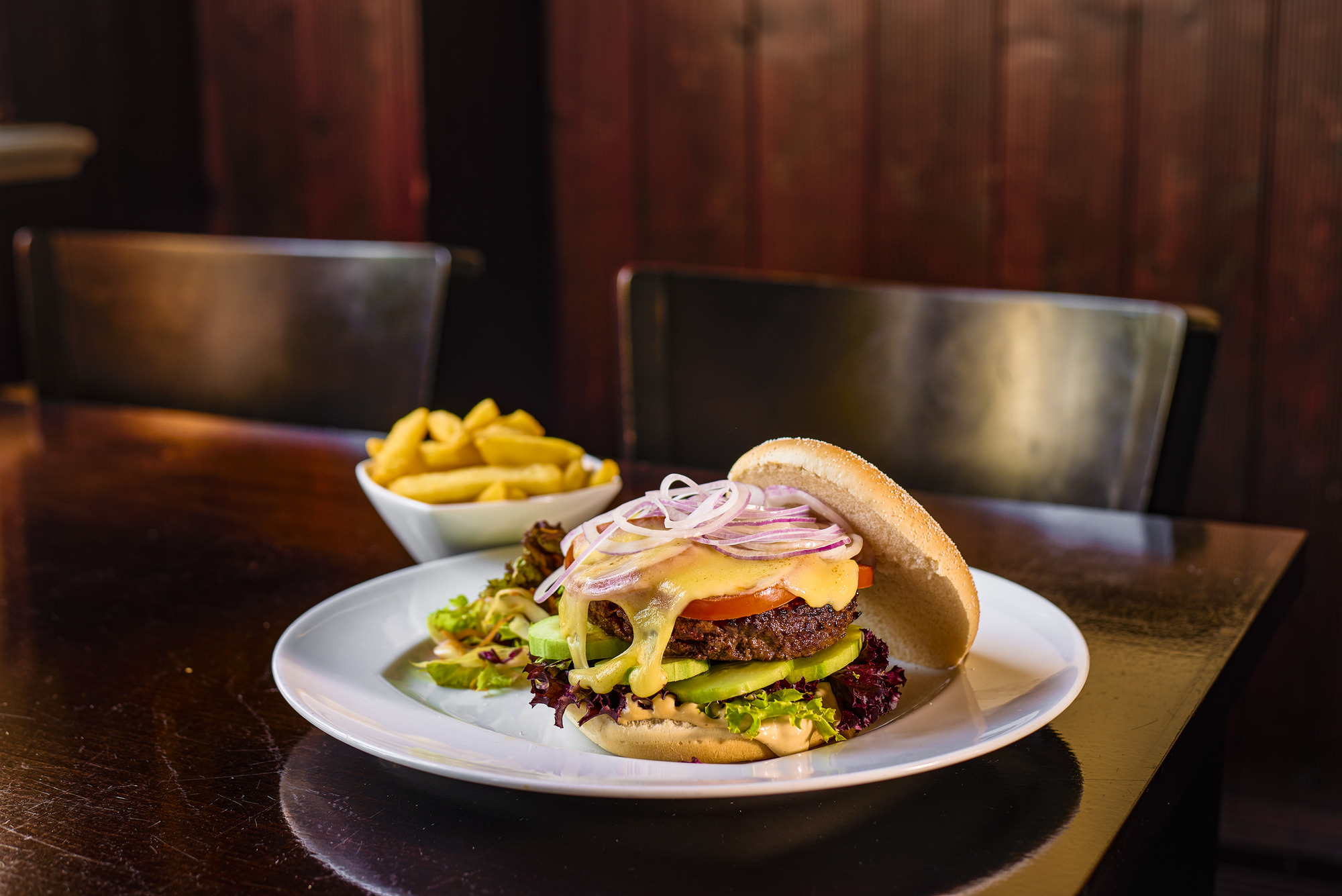 Burger mit Salat und Zwieblen auf einen weißen Teller 